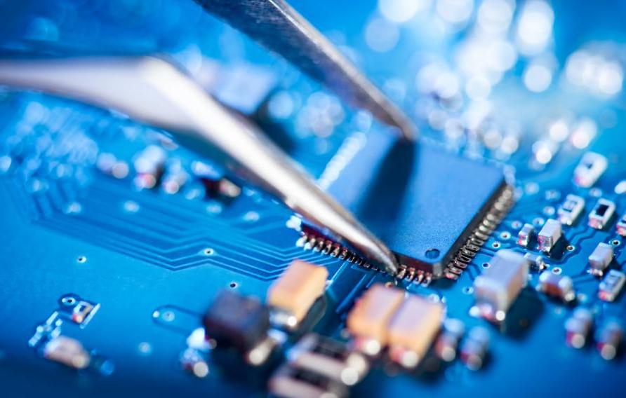  Electronic technician holding tweezers and assemblin a circuit board.